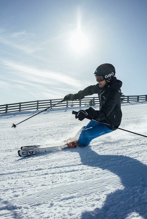 Ein Skifahrer in Action auf der Piste, mit strahlendem Sonnenschein und klarem Himmel