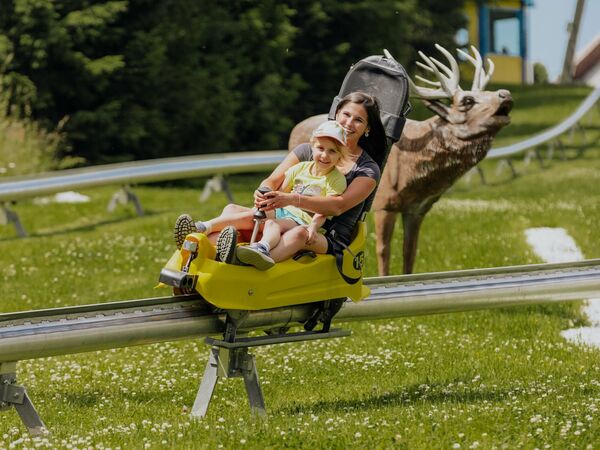 Mutter und Tochter fahren gemeinsam auf der Rodelbahn